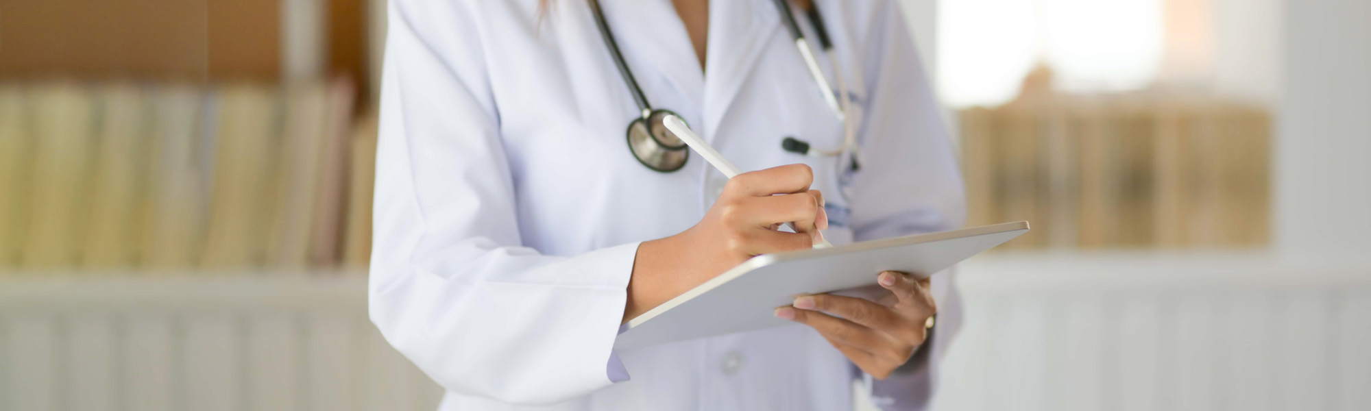 Cropped shot of young doctor checking patient chart while using digital tablet