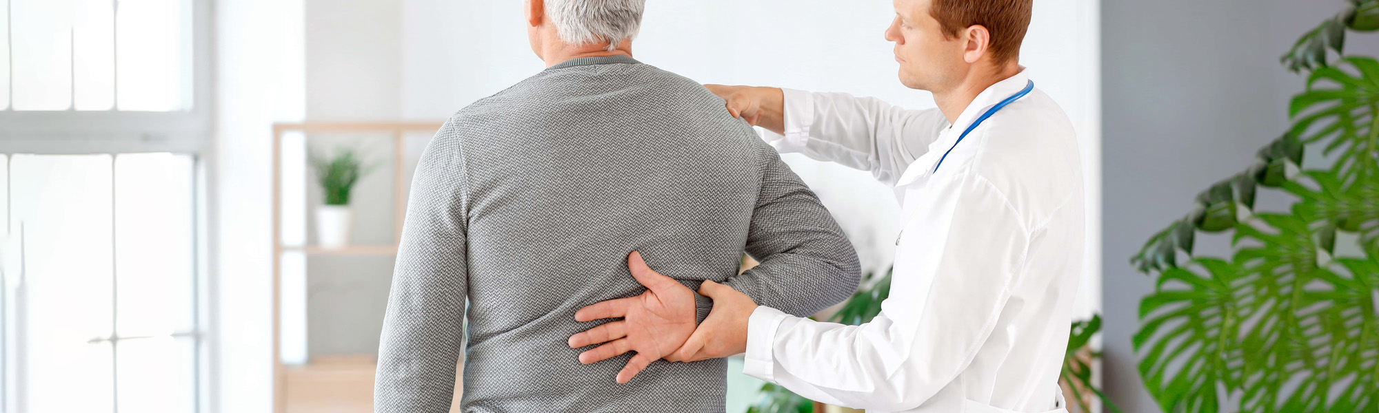 Doctor examining mature man with joint pain at home