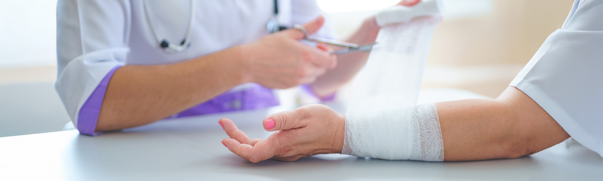 Doctor is bandaging wrist of patient in clinic