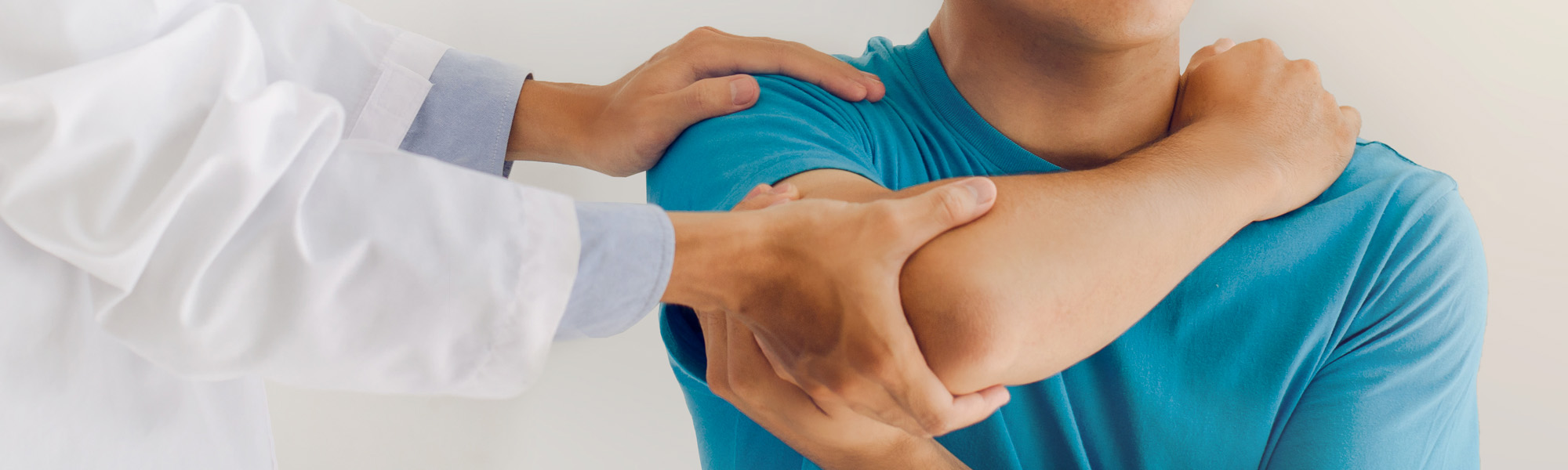 Doctors or physical therapists work to treat the injured arm of a male patient who has performed muscle treatment
