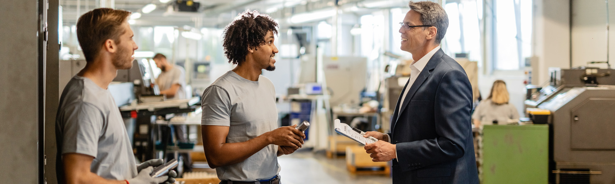Happy businessman talking with metal workers
