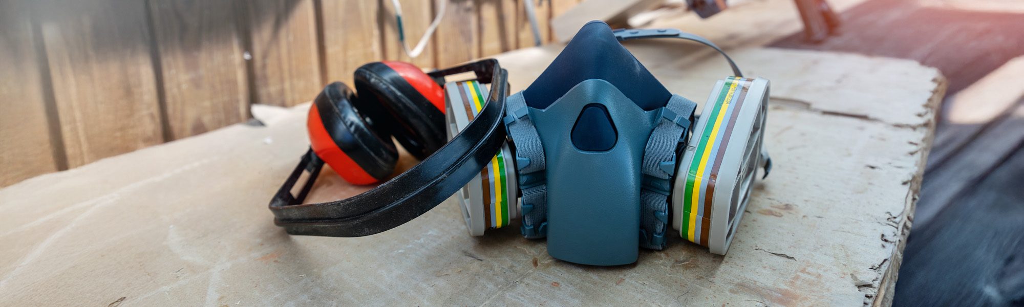 PPE respirator face half mask and ear protection equipment on wooden workbench