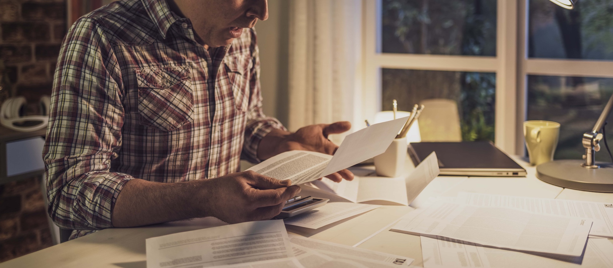 Shocked man checking bills at home