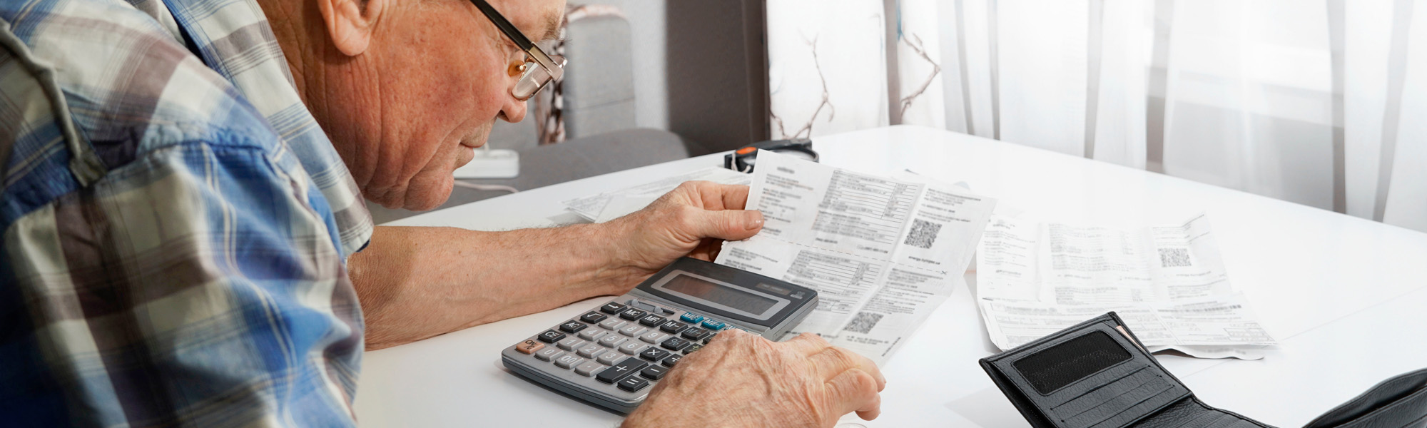 Upset Senior man sitting at the table and calculating finances