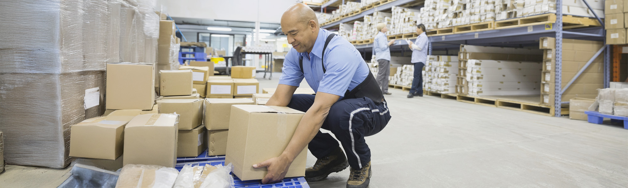 Worker lifting cardboard boxes in warehouse