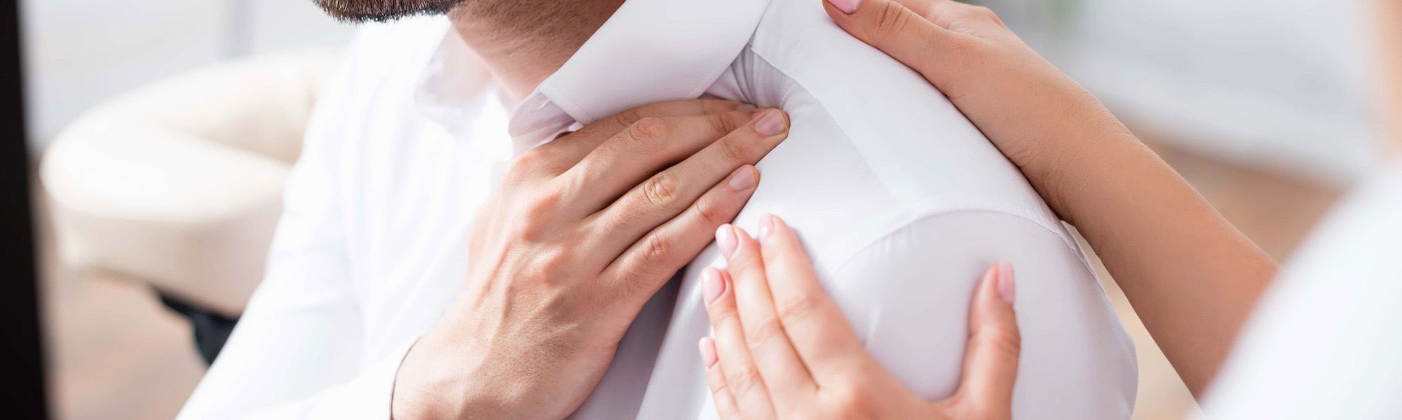 cropped view of masseuse touching painful shoulder of businessman in office on blurred foreground