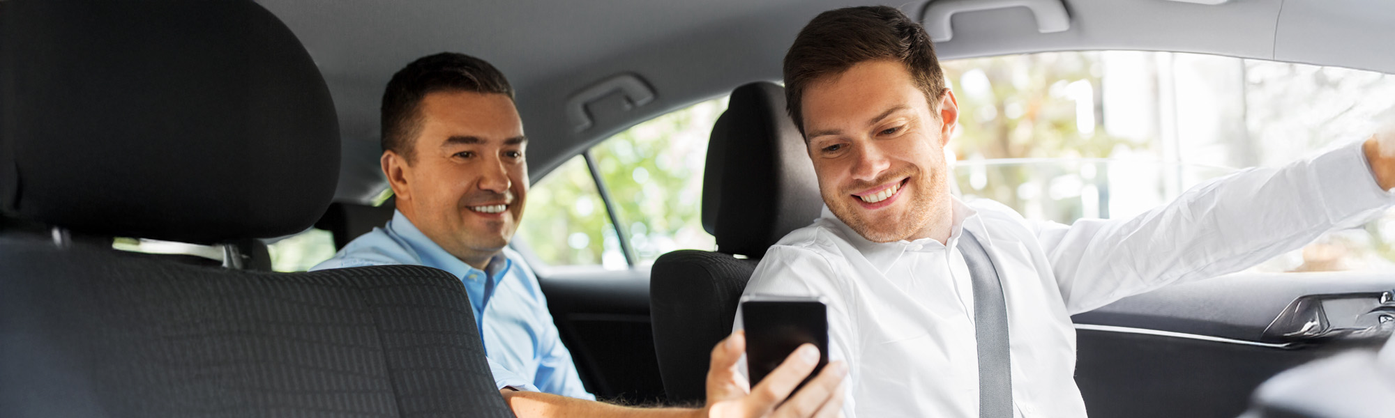 male passenger showing smartphone to car driver