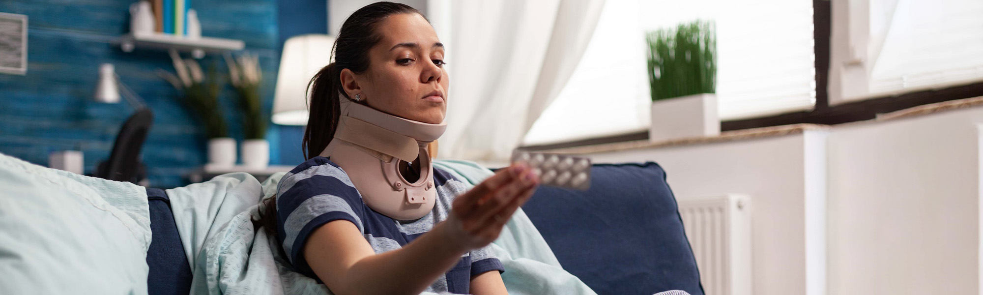woman in neck brace suffering from pain on sofa