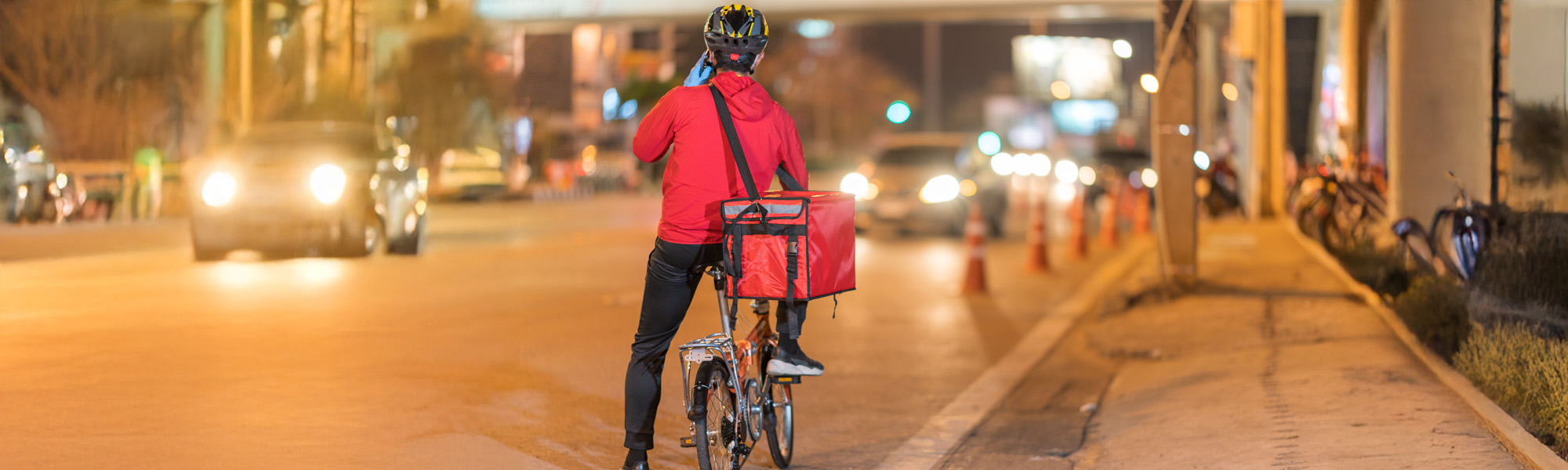 young man working for a food delivery service checking with road bicycle in the city