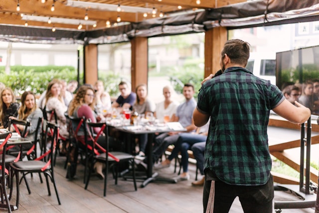 people sitting at table with man on microphone