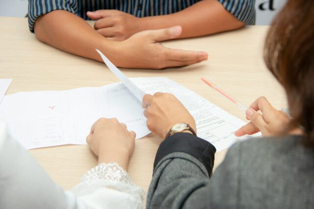 man sitting at a table with people and documents